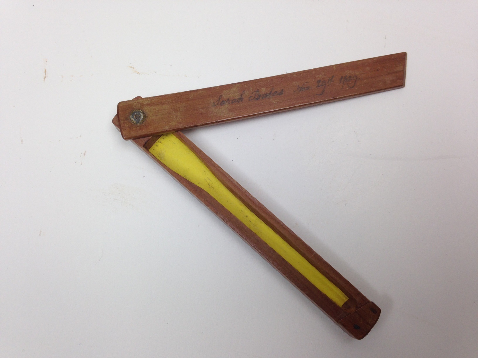 A wooden ruler with a yellow piece of paper on it.