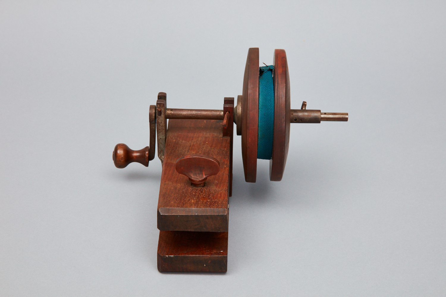 A wooden spinning wheel with a blue spool.