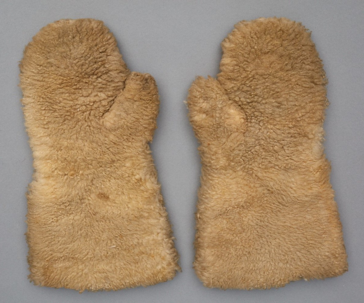 A pair of brown mittens on a gray surface.