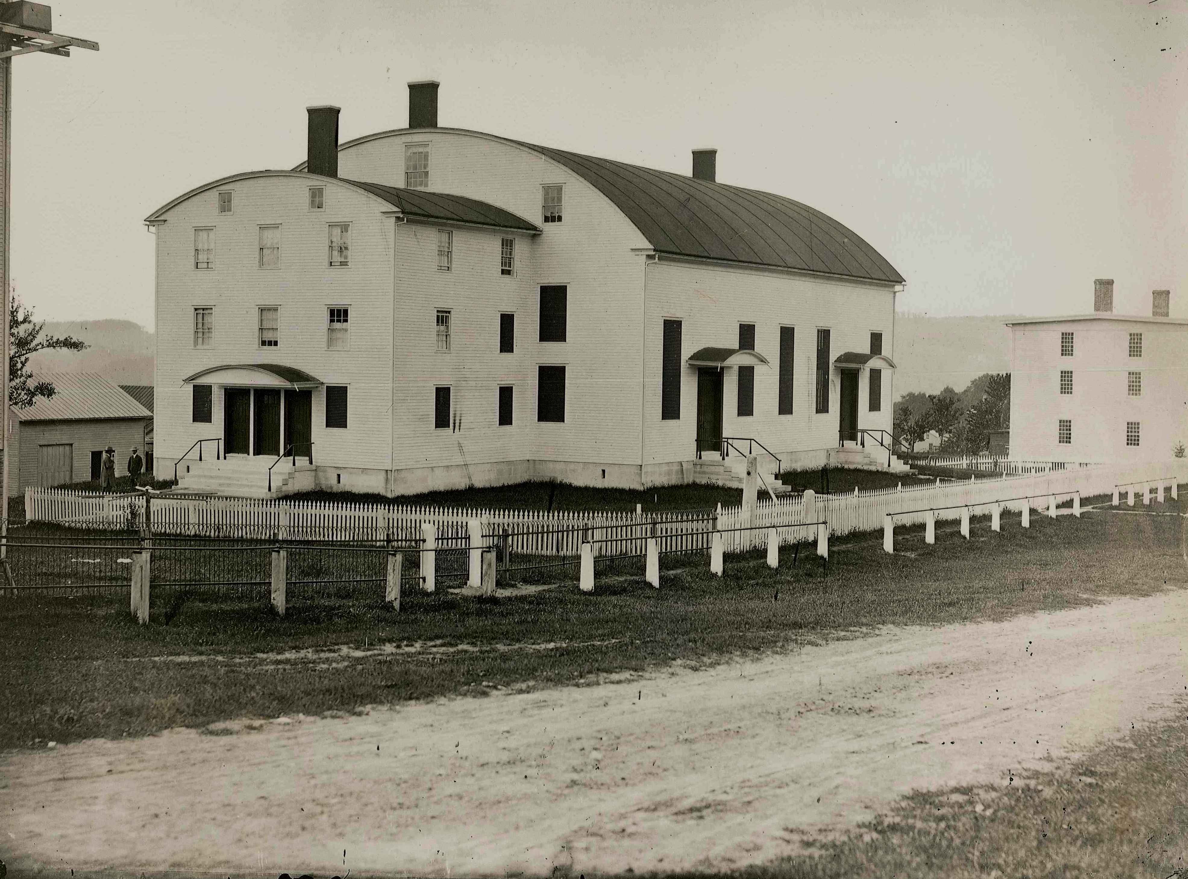 An old photo of a white house on a farm.