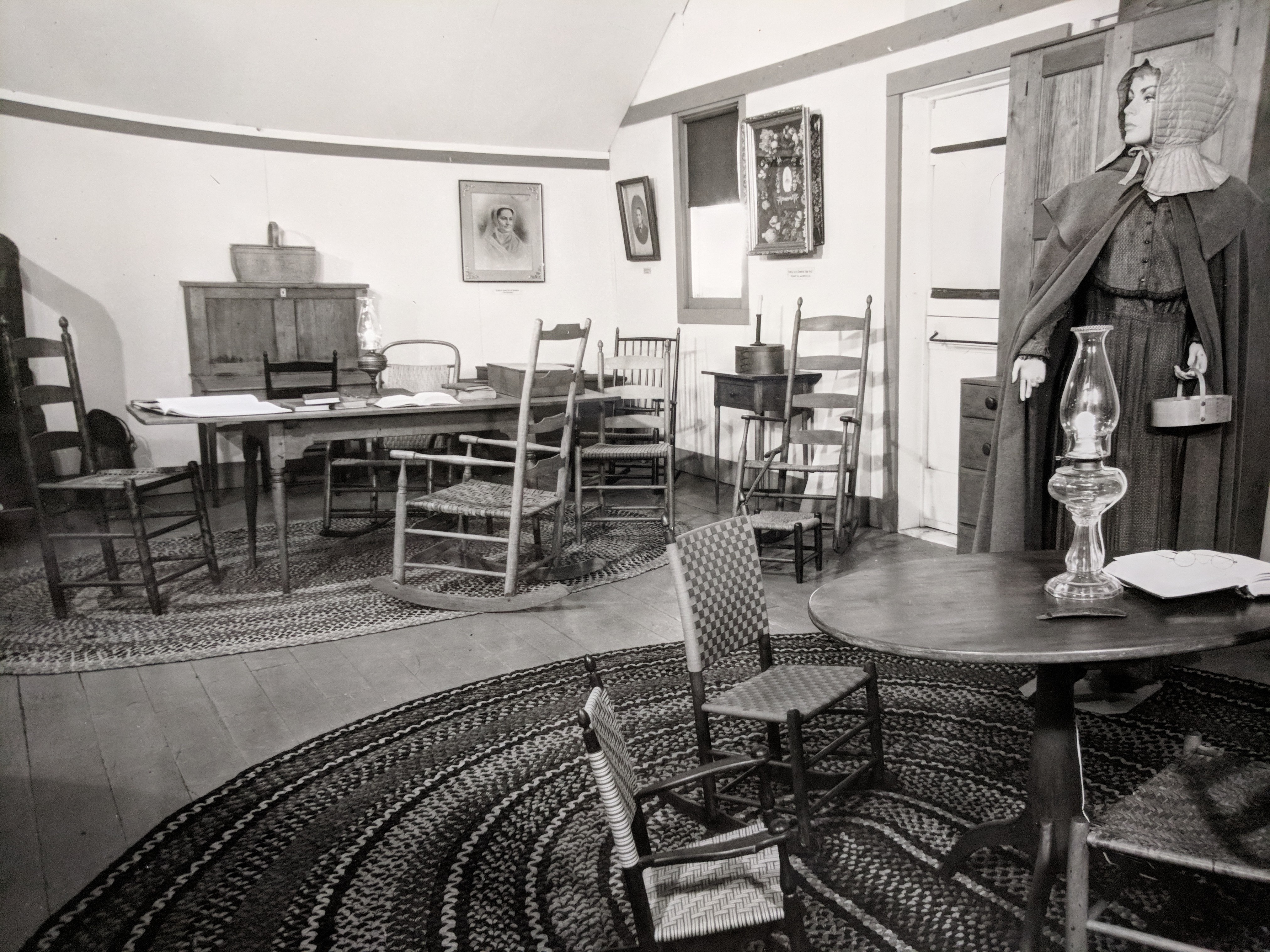 A black and white photo of a room with chairs and a table.