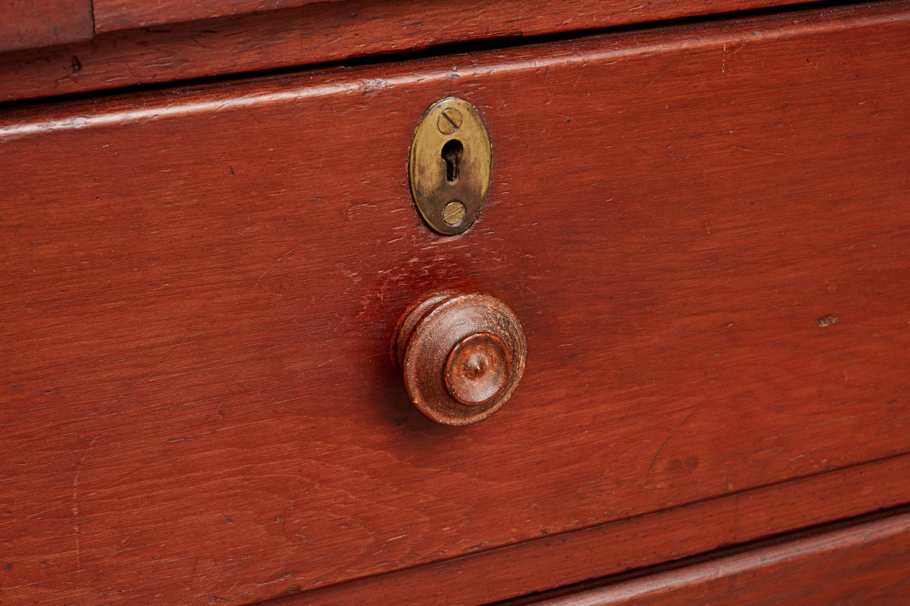 A close up of a knob on a wooden dresser.