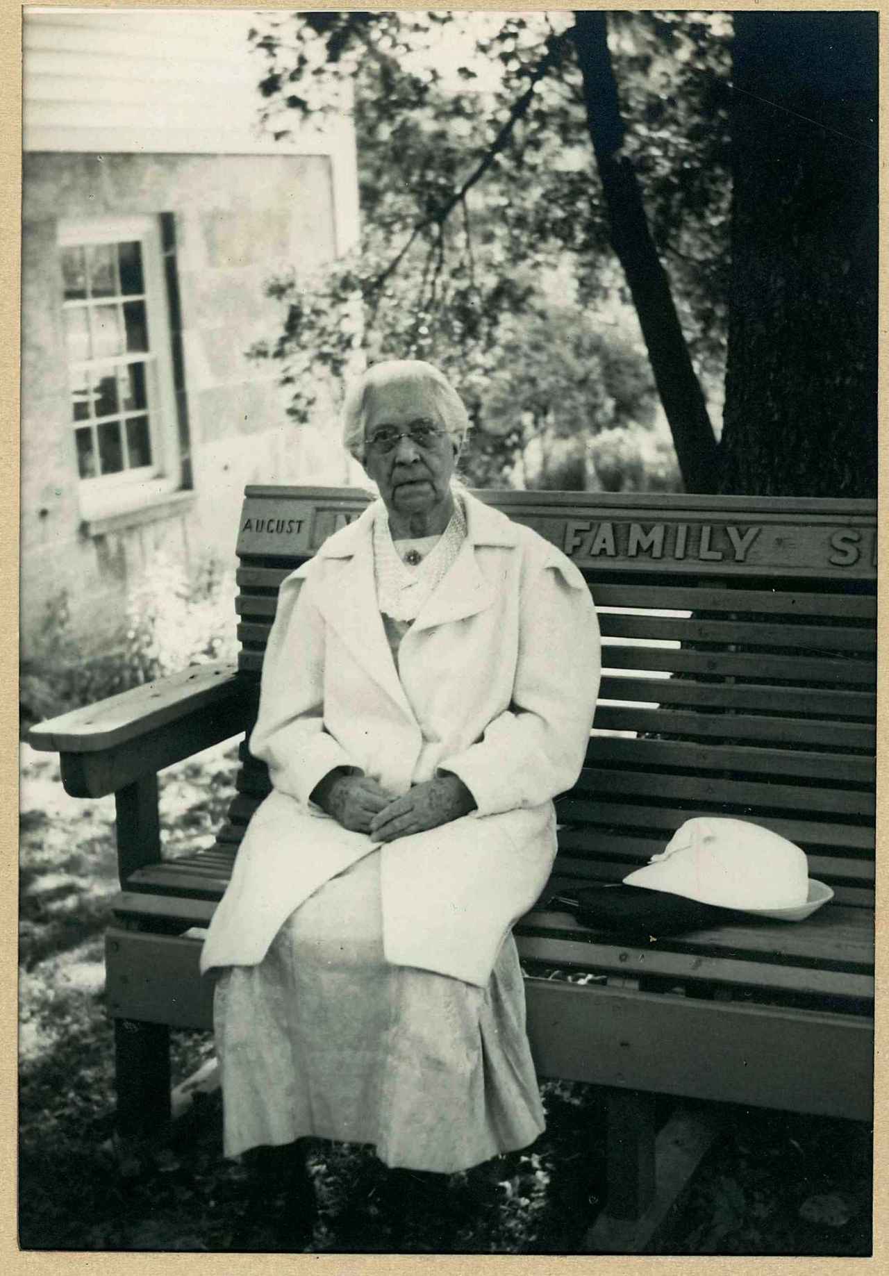 A woman in a white coat sitting on a bench.