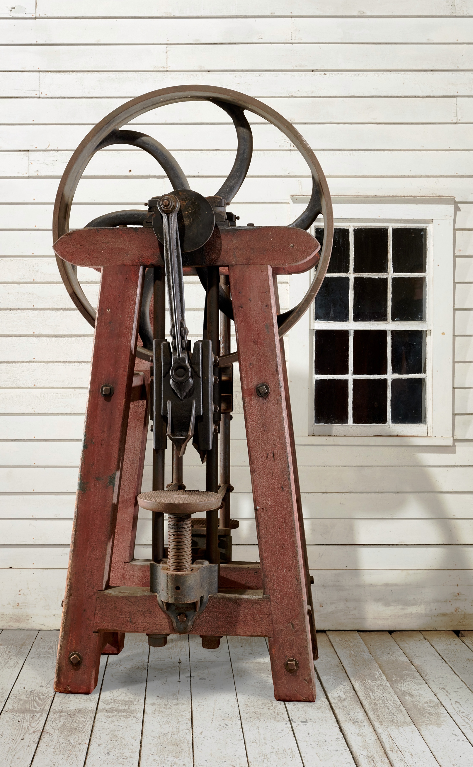 A wooden machine is sitting on a wooden floor in front of a window.