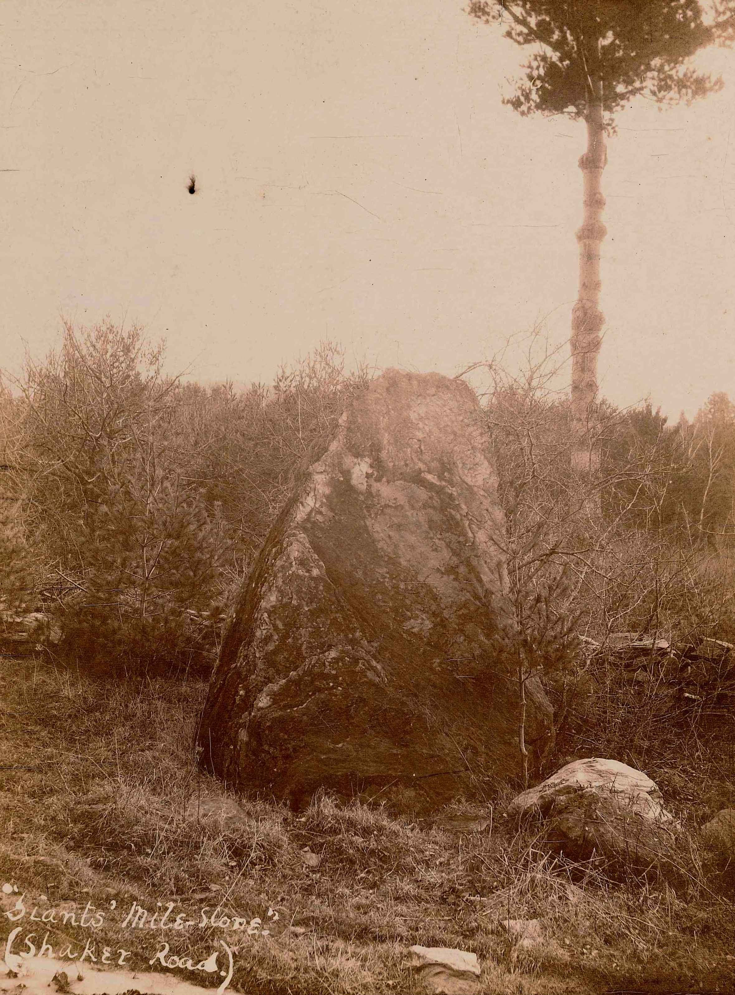 An old photo of a large rock in a field.