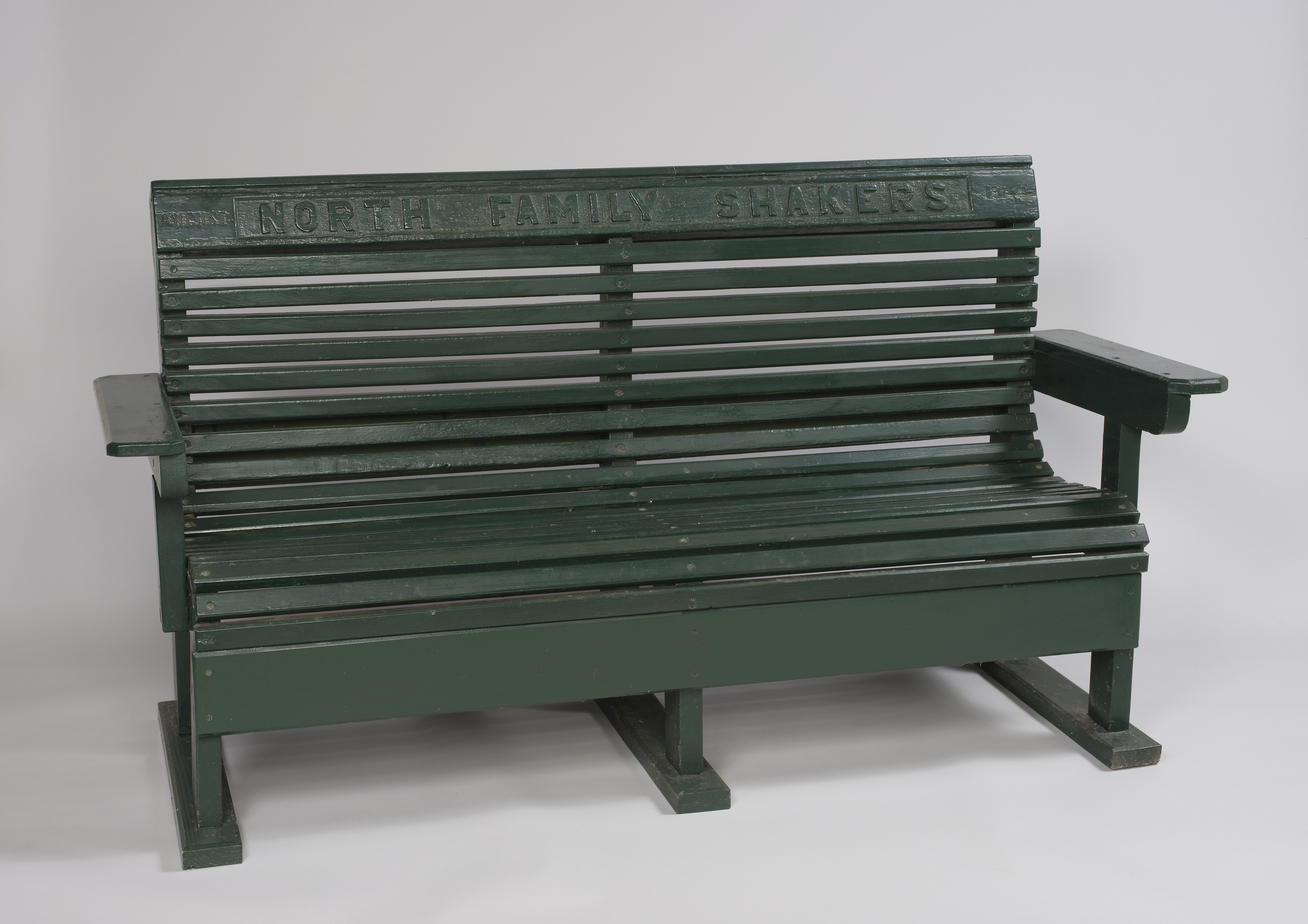 A green bench with a sign on it.