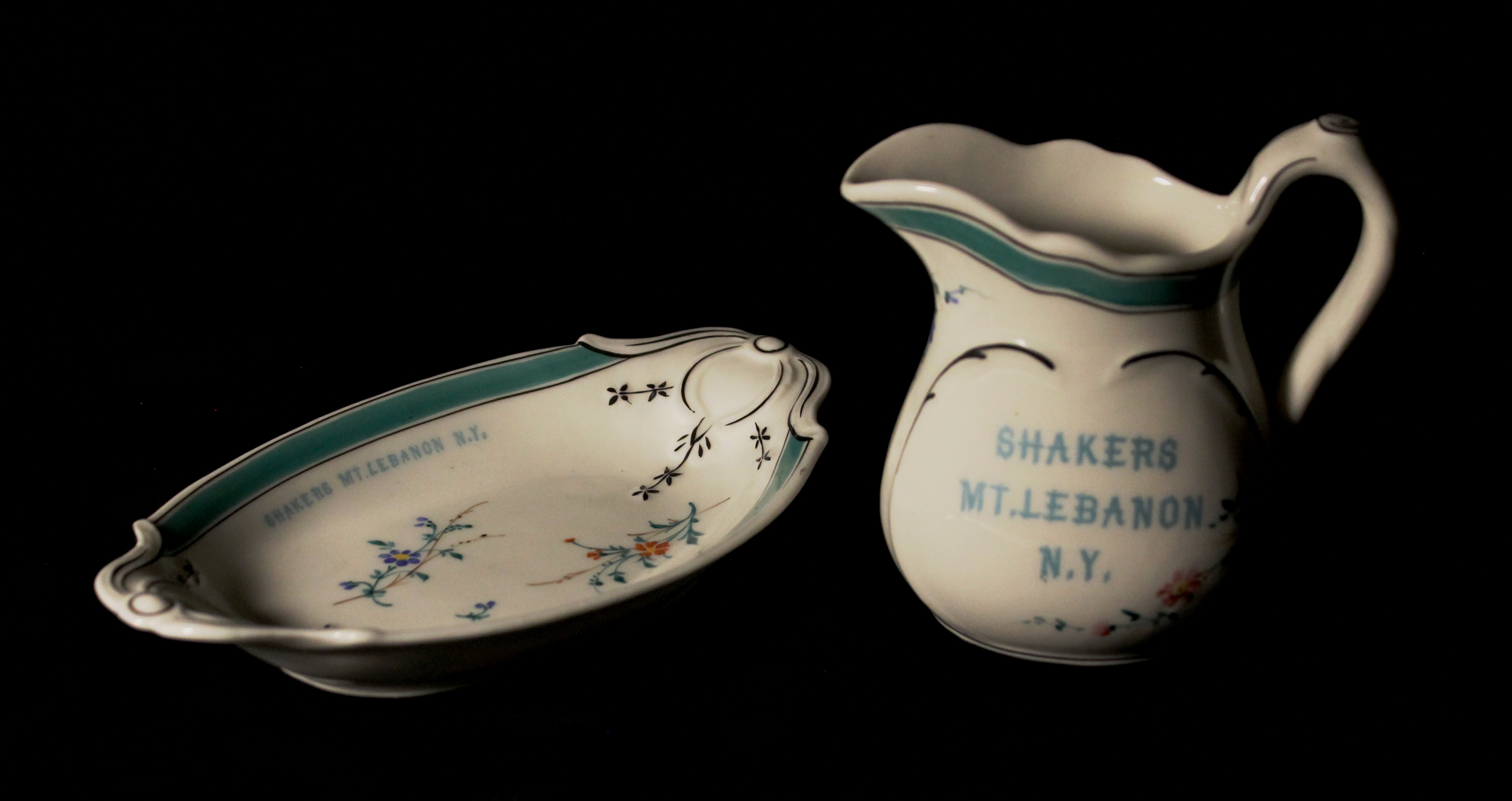 A pitcher and a bowl on a black background.