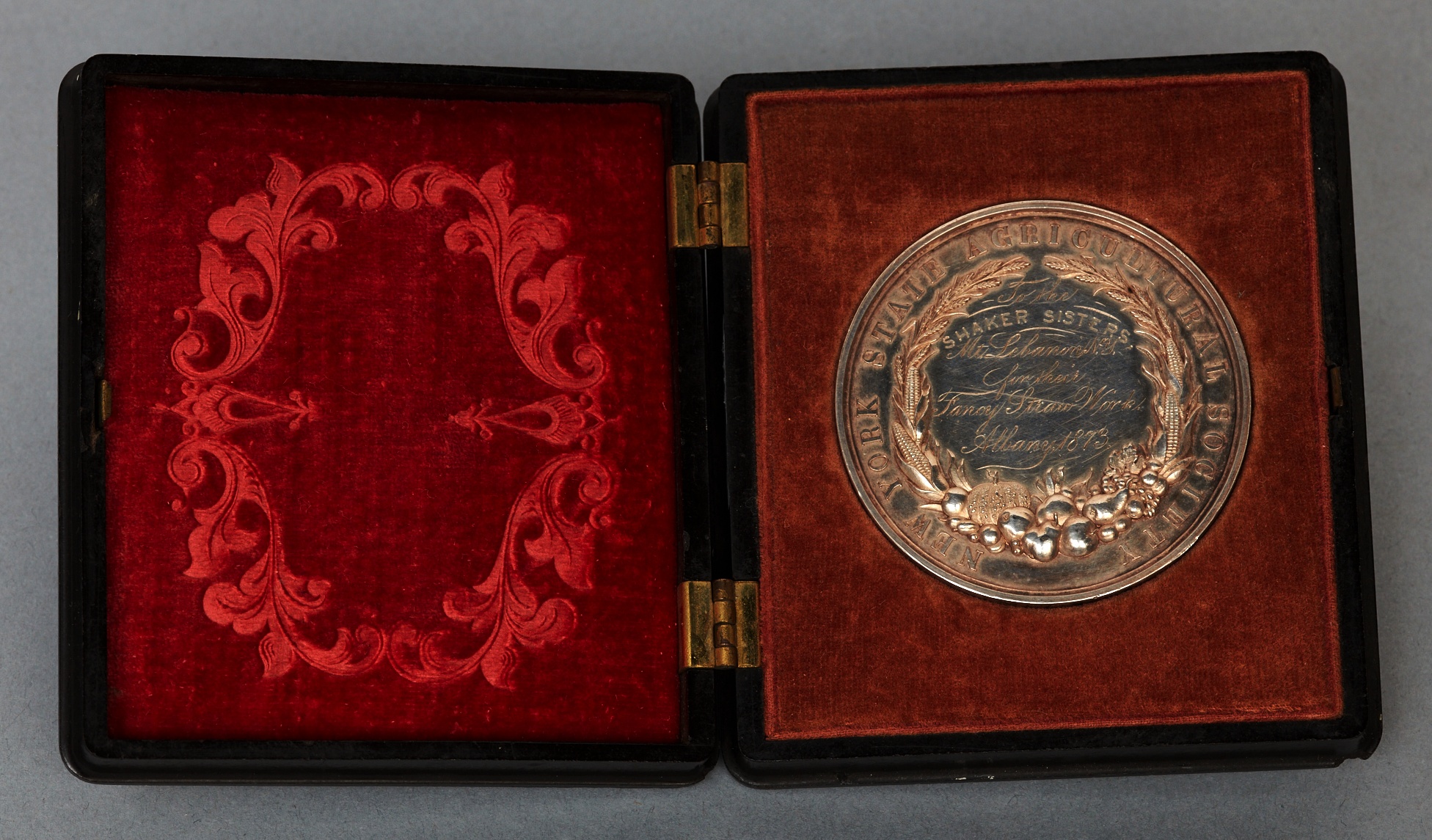 A silver medal in a red and black case.