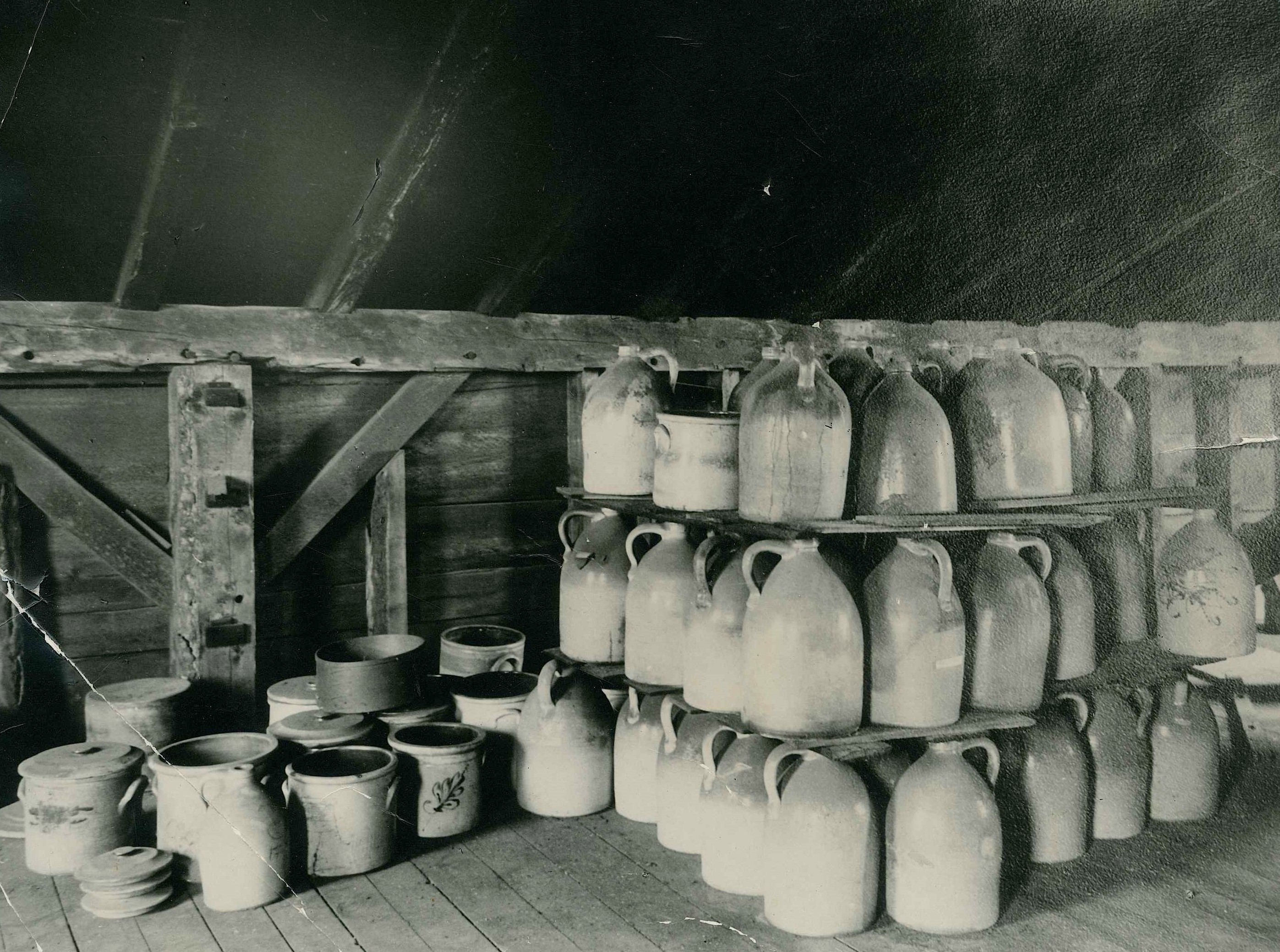 An old black and white photo of many jugs in a room.