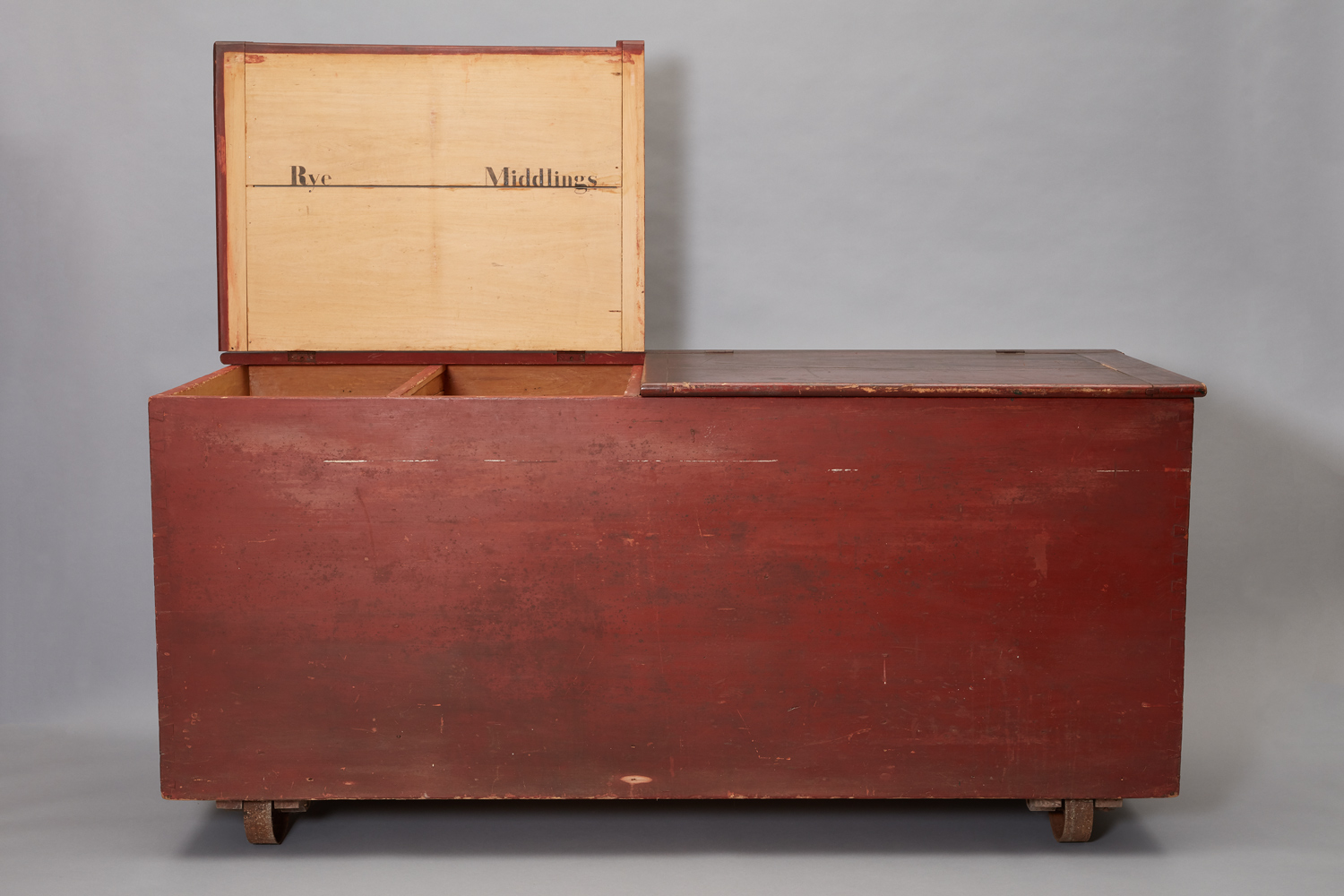 A red chest on wheels with a wooden top.