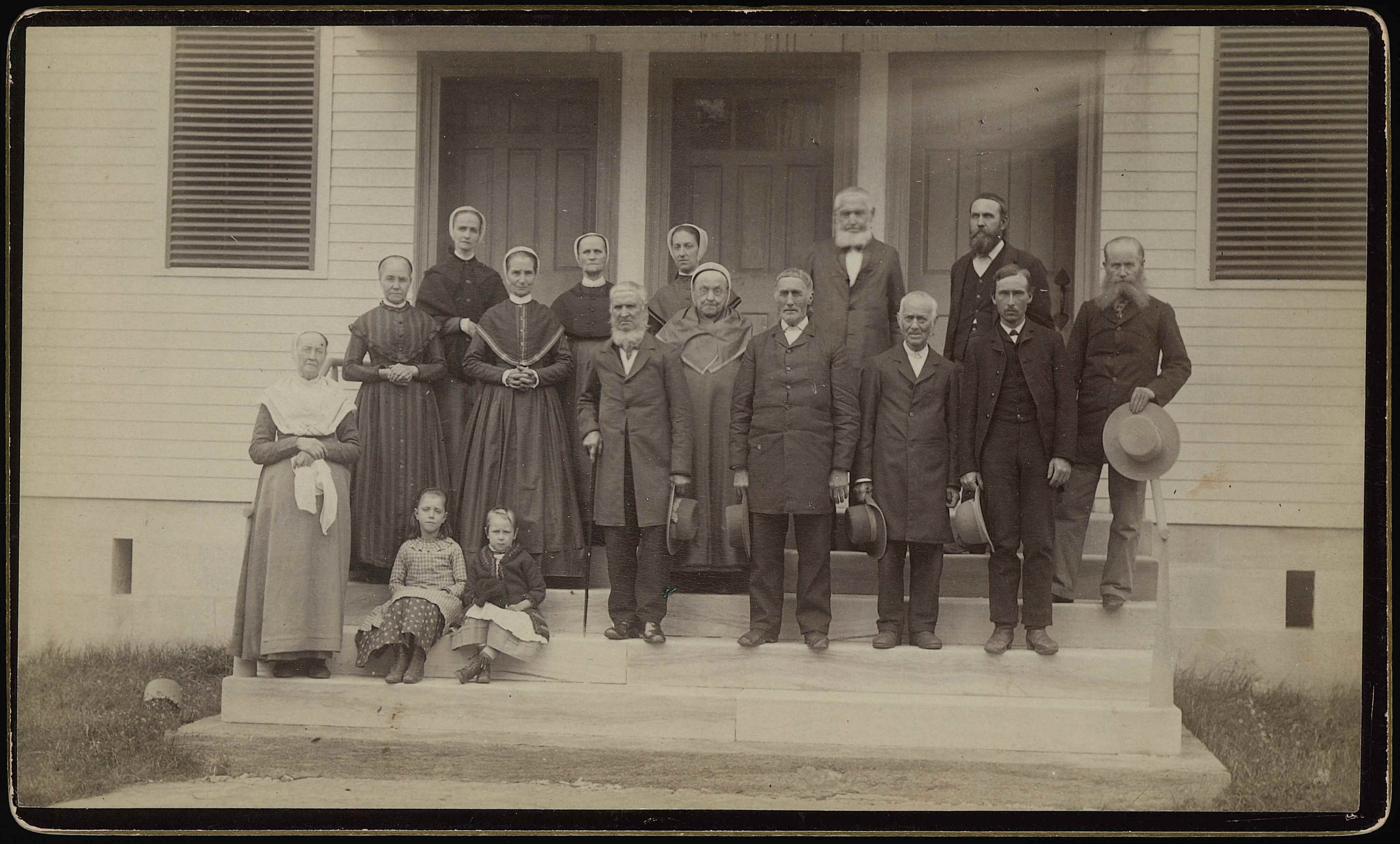 A group of people standing on the steps of a house.