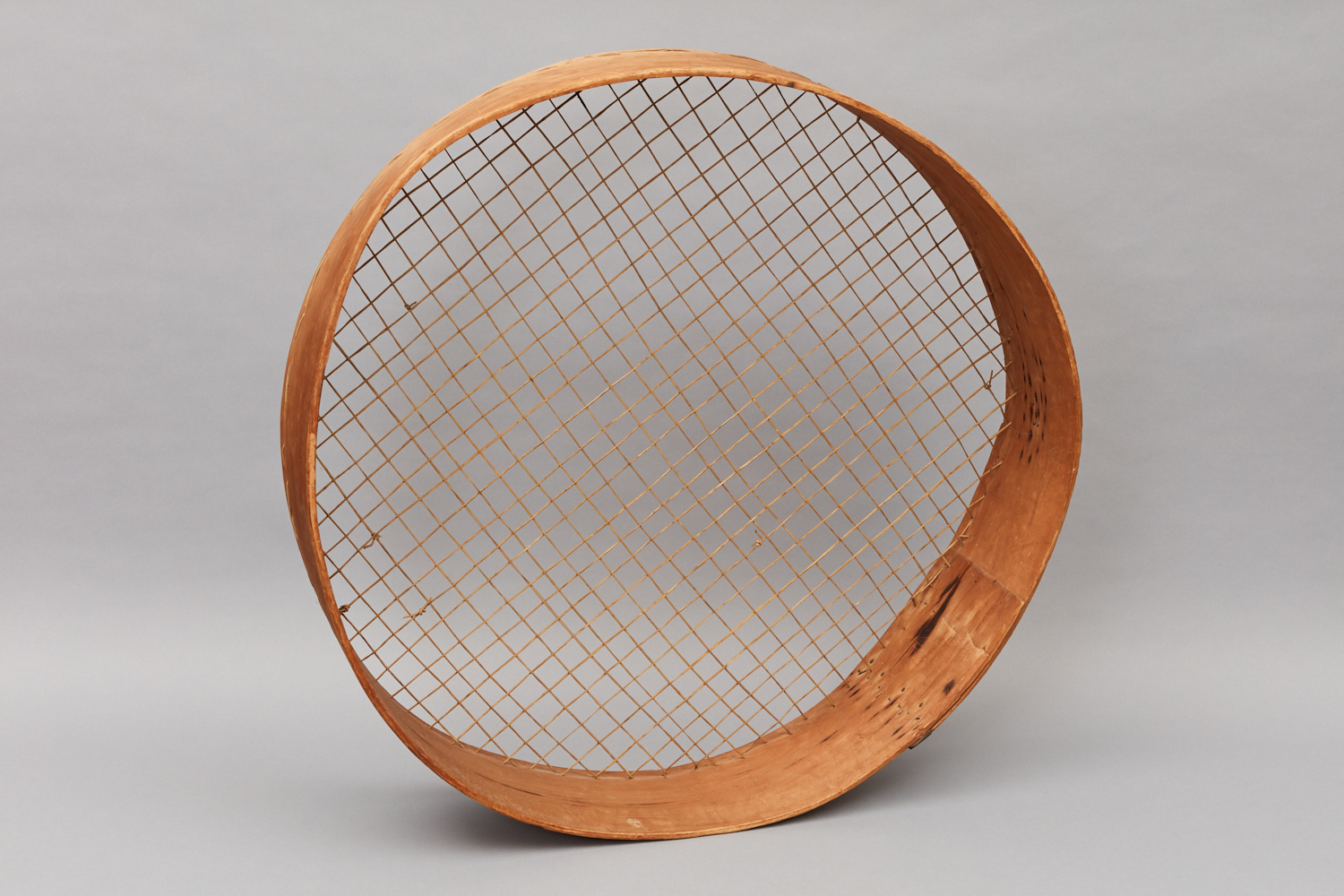 A circular wooden sculpture with a wire frame.