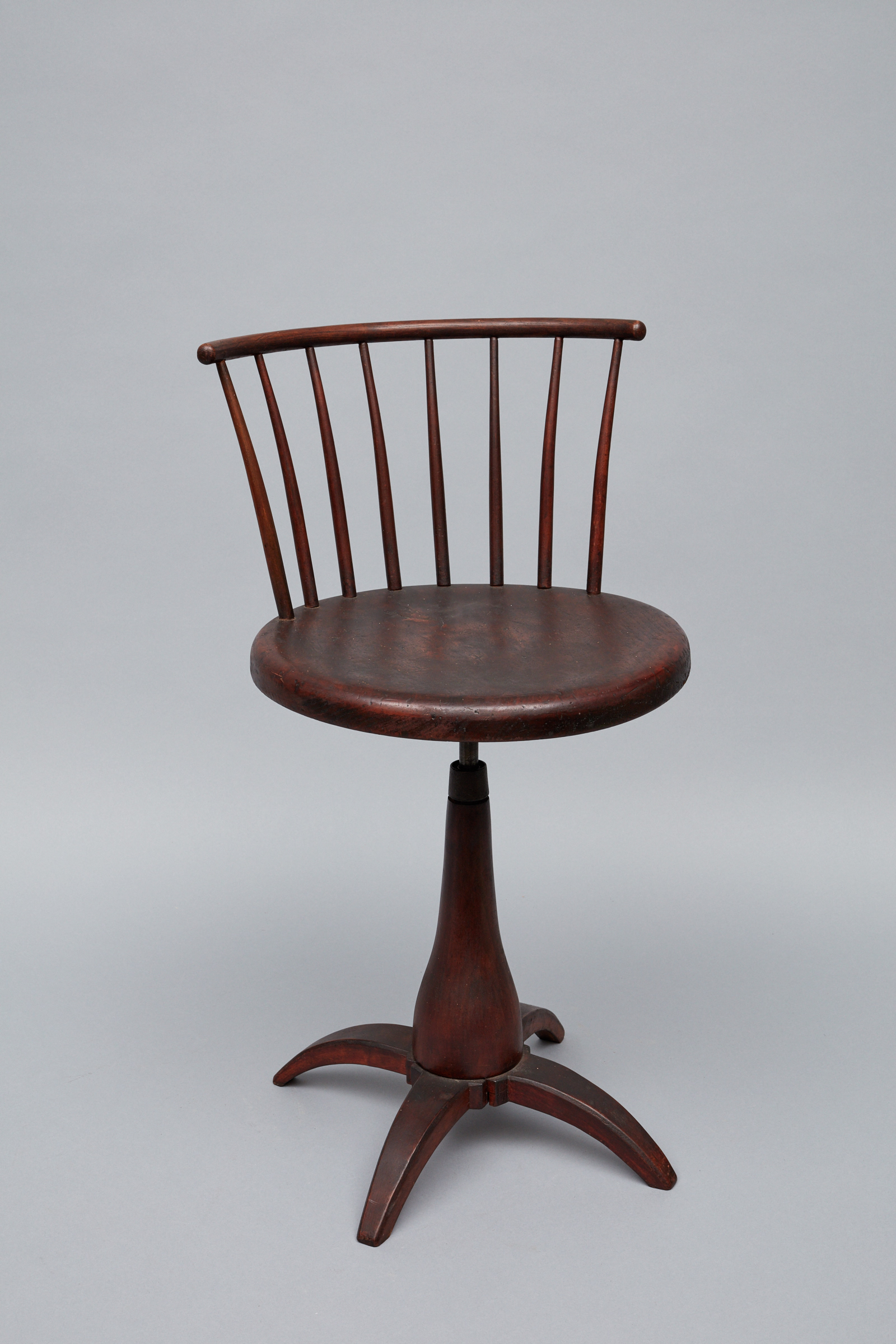 A wooden swivel chair on a pedestal.