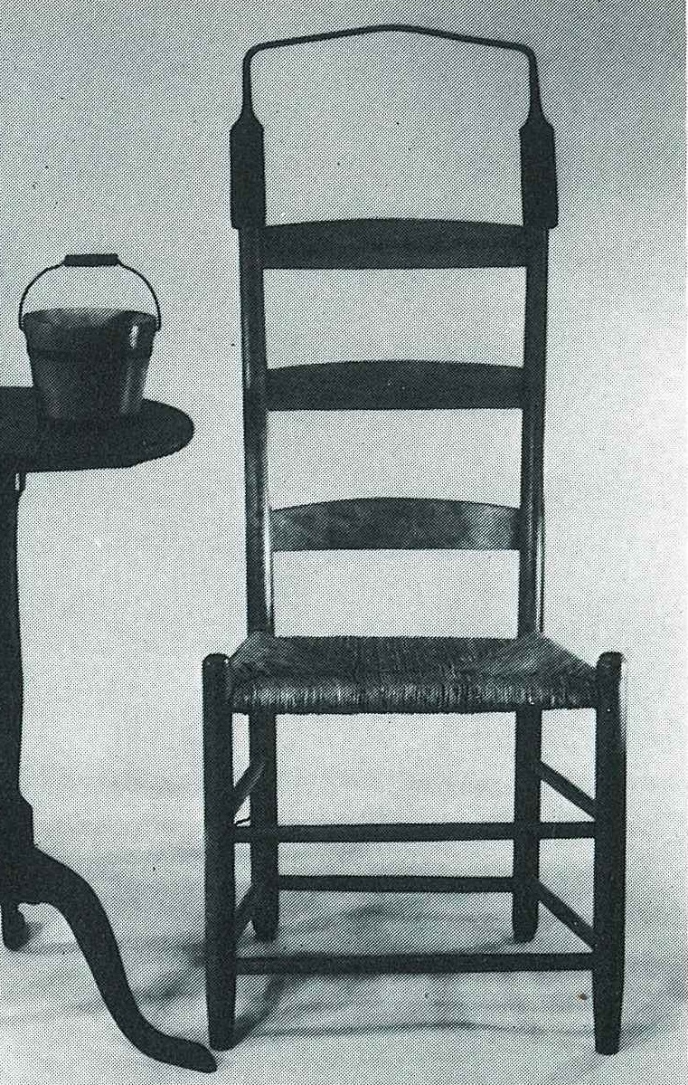 A black and white photo of a chair and table.