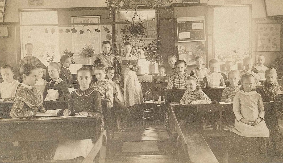 An old photo of a classroom with children sitting at desks.