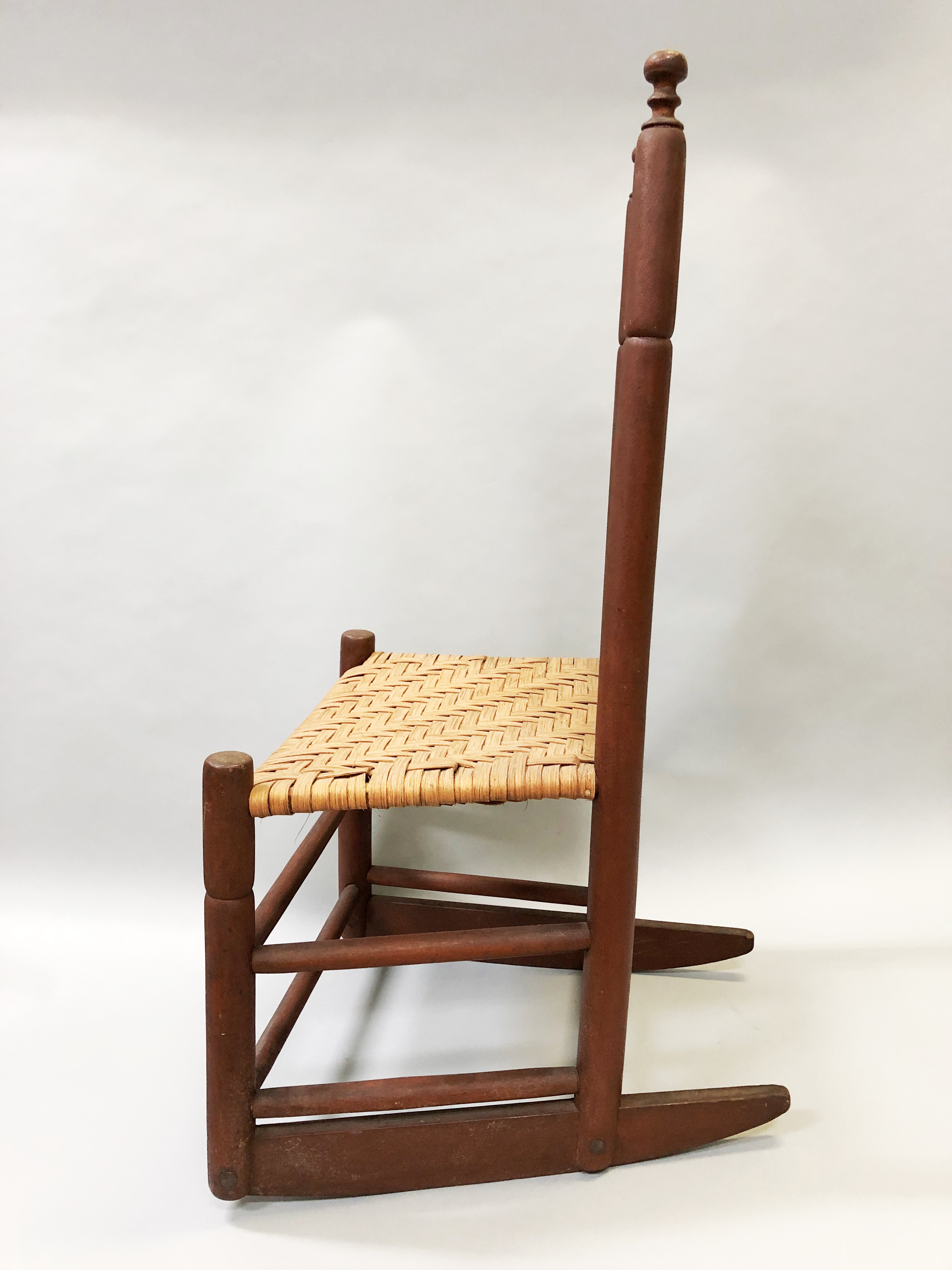 A wooden rocking chair with a wicker seat.