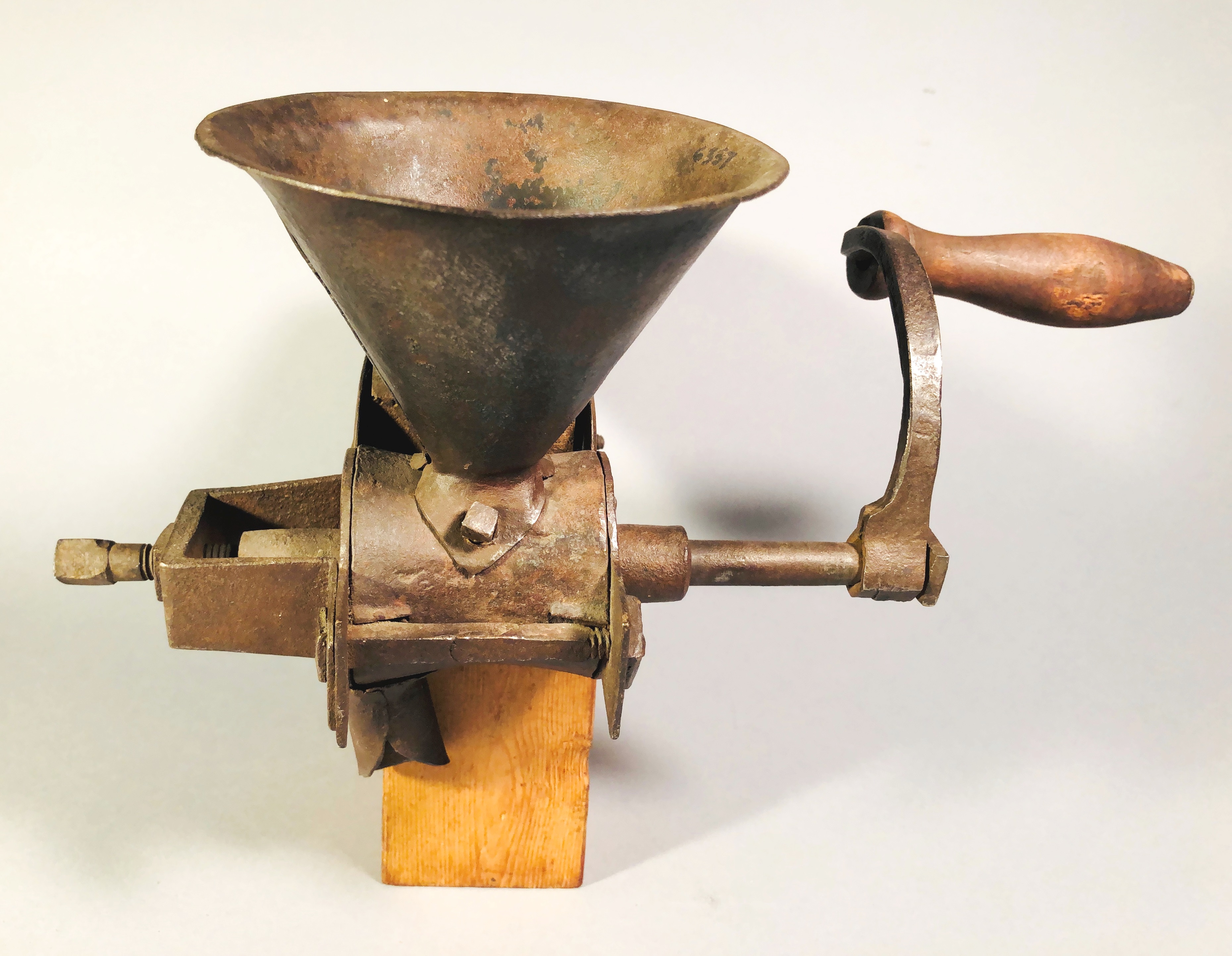 An old fashioned coffee grinder on a wooden base.