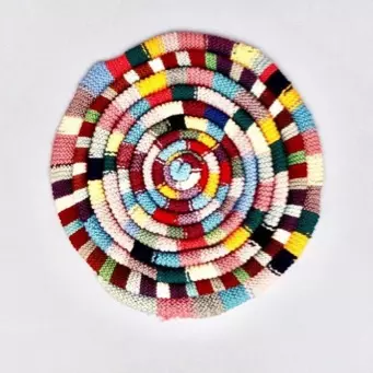 A colorful woven placemat on a white surface.