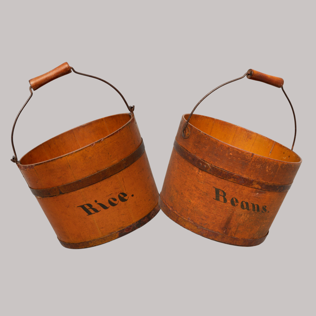 Two orange wood and metal Shaker buckets with handles. One labeled "Rice" and the other "Beans.